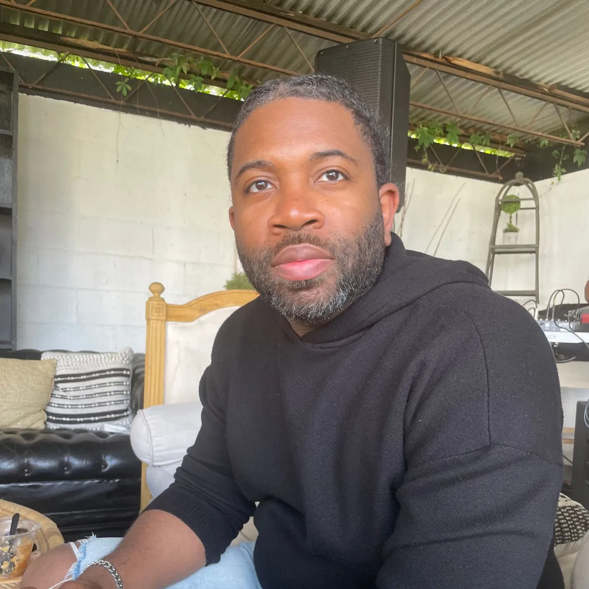 Douglas on a covered patio, in a black hoodie